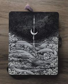 a black and white drawing on top of a piece of paper with a crescent hanging from it