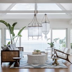 a living room with two chairs and a table in front of large windows that look out to the ocean