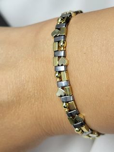 a close up of a person's arm wearing a gold and silver chain bracelet