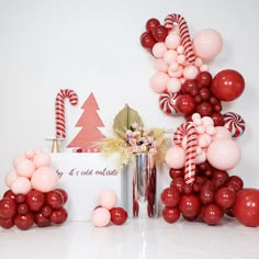 balloons and candy canes are on display in front of a white wall with red and pink decorations