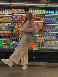 a woman walking past a store filled with drinks