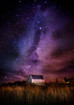 the night sky is filled with stars above a small white house and grass in front of it