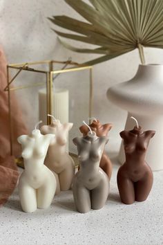 four small ceramic deer figurines sitting on a table next to a potted plant