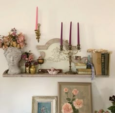 there is a shelf with candles and pictures on it