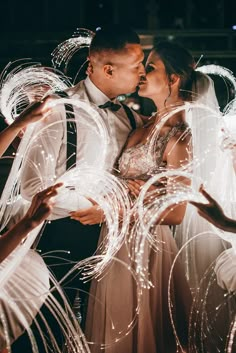 a bride and groom kissing in front of sparkle streamers at their wedding reception on the dance floor