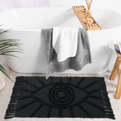 a bathroom with a bathtub, rug and towel on the floor in front of it