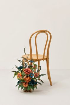 a wooden chair sitting next to a bouquet of flowers