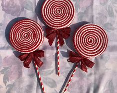 three red and white lollipops with bows on them