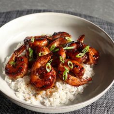 a white bowl filled with rice covered in sauce and chicken wings on top of it