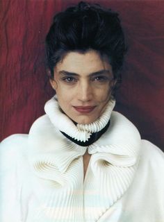 a woman wearing a white sweater and black collared necktie, posing for the camera