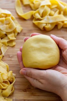 a person holding a doughnut in front of some uncooked pasta on a cutting board