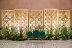 a green couch sitting in front of a wall with flowers and greenery on it