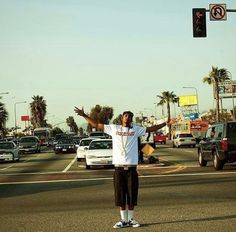 a man standing on the side of a road holding his arms up