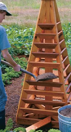 a man standing next to a wooden ladder in the middle of a garden filled with plants