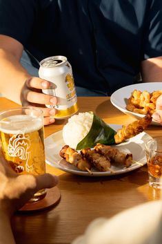 two people sitting at a table with plates of food and beer in front of them