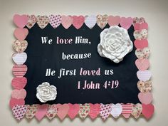 a sign with hearts and flowers on it that says, we love him because he first loved us 1 john 19