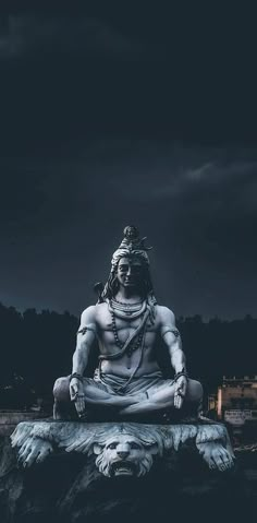 an image of a statue that is sitting on the ground in front of a dark sky