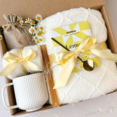 an open box containing a coffee cup, mug and teaspoon with a yellow ribbon