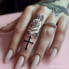 a woman's hand with a rose and cross tattoo on the middle ring finger