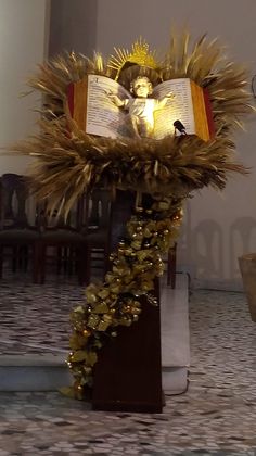 an open book on top of a table next to a wreath with a statue of jesus in it