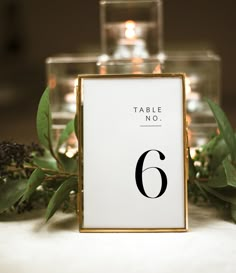 a table number with candles and greenery in the background