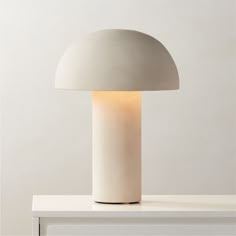 a white lamp sitting on top of a table next to a light bulb in the shape of a mushroom