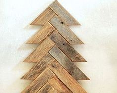 a wooden christmas tree sitting on top of a hard wood floor next to a white wall