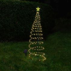 a lighted christmas tree in the grass at night