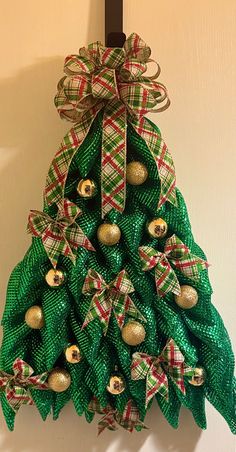 a christmas tree made out of green mesh and gold ornaments hanging on a door hanger