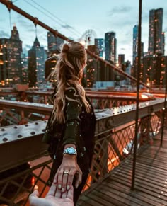 a woman holding the hand of another person on top of a bridge in new york city