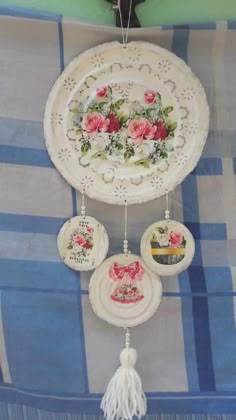 a decorative plate hanging from the ceiling with flowers and tassels attached to it