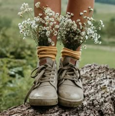 a pair of boots with flowers tied to them on top of a tree stump in the woods