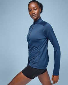 a woman in blue shirt and black shorts posing for the camera with her hands on her hips