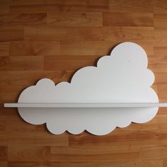 a white cloud shaped shelf on a wooden floor