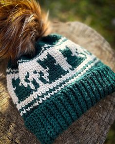 a green and white knitted hat on top of a tree stump with text overlay that reads tapestry crochet cat hat