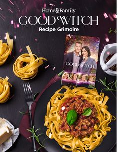 a black plate topped with spaghetti next to a cookbook