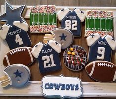 decorated cookies are arranged in the shape of american footballs and sports jerseys on a tray