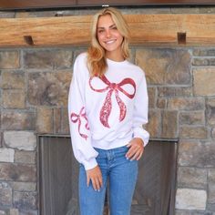 Pink crewneck sweater with a red Christmas bow on the front