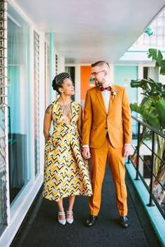 a man and woman dressed in orange are walking down the hallway together, holding hands