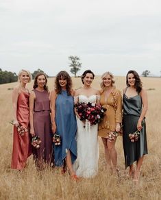 a group of women standing next to each other on top of a dry grass field