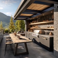 an outdoor kitchen and dining area with mountains in the background