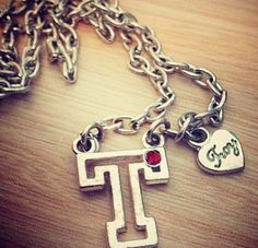 a close up of a necklace on a table with a heart and two charms attached to it