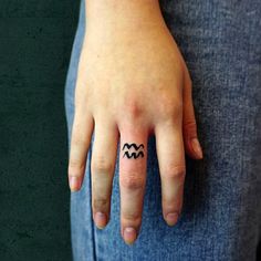 a woman's hand with a small tattoo on her left thumb and an arrow in the middle