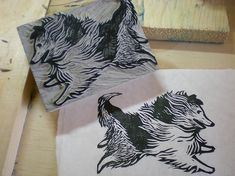 two black and white dogs on paper next to some wood