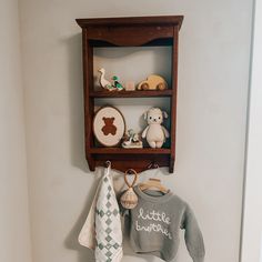 a wooden shelf with stuffed animals and sweaters hanging from it's hooks on the wall