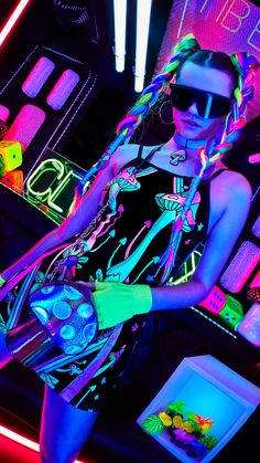 a woman with neon hair and sunglasses is posing in front of some neon colored lights