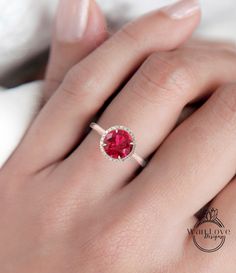 a woman's hand with a ring on it and a red stone in the middle