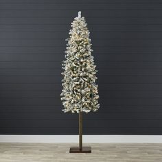 a white christmas tree with snow on the top and branches in front of a black wall