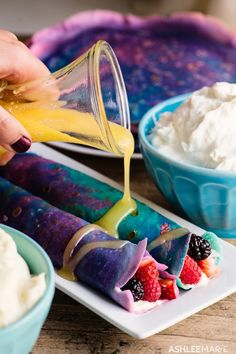 someone is pouring something into some desserts on a plate with strawberries and whipped cream