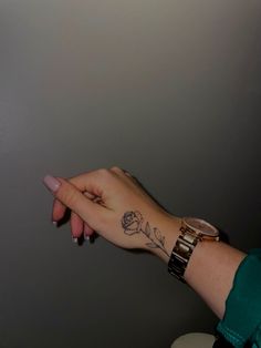 a woman's hand with a rose tattoo on it and a watch around her wrist